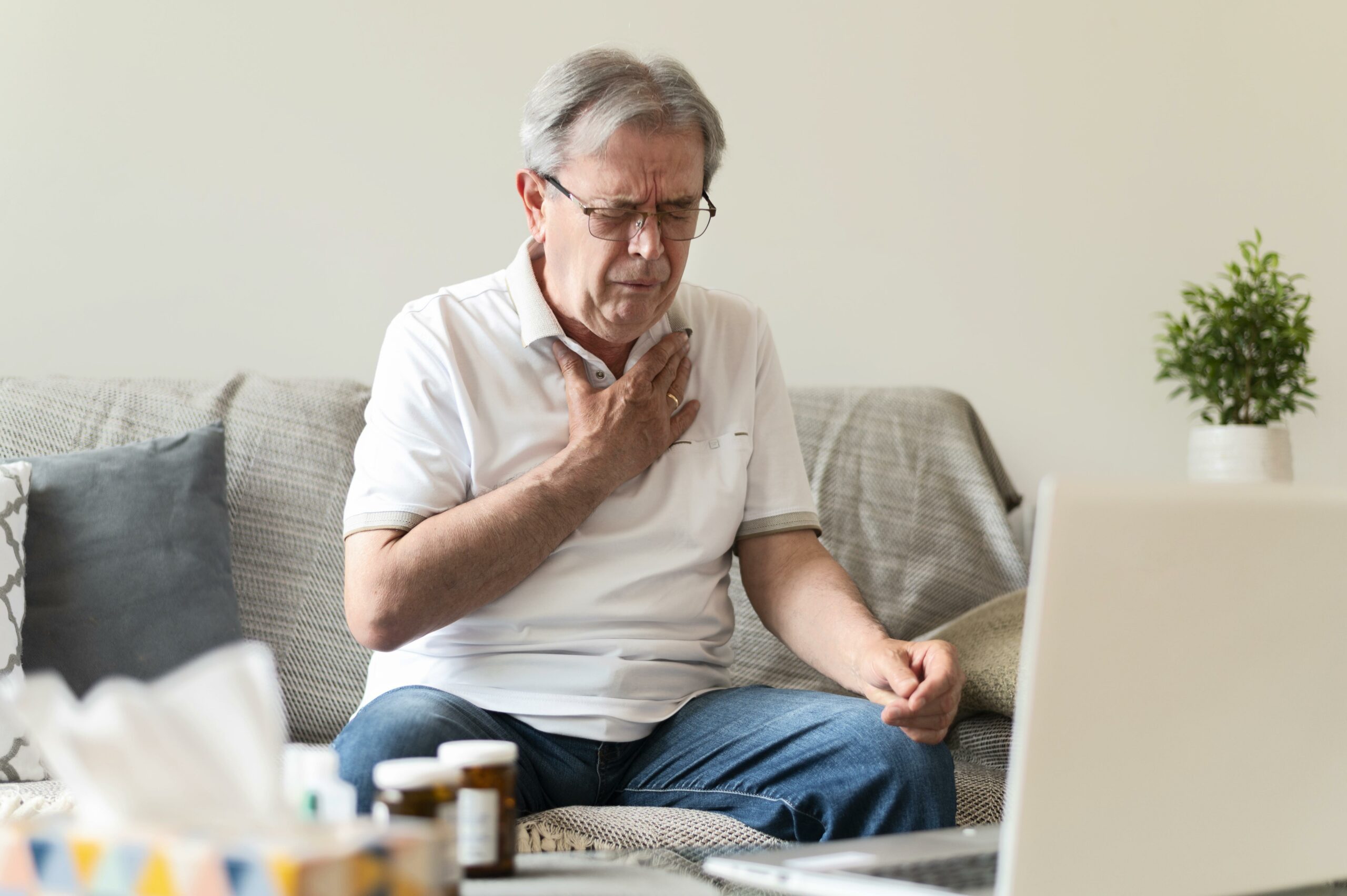 Senior man experiencing symptoms and consulting an Ibis Health doctor from home.