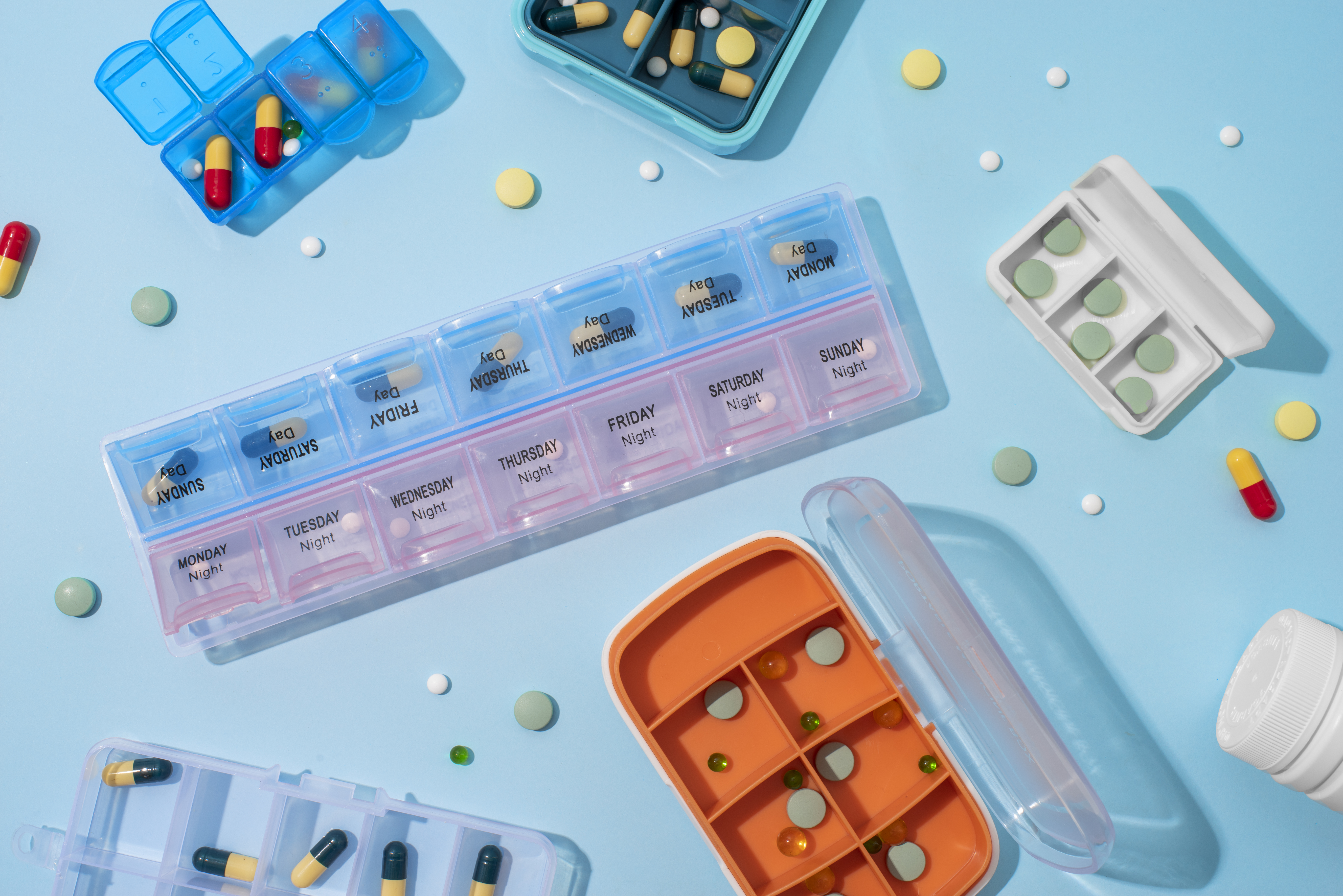 Daily pill organizers and tablets laid out for medication tracking.